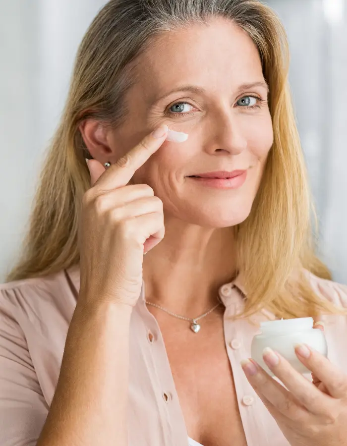 An old lady preventing from looking older and getting skin aging by applying the right creams on her face.