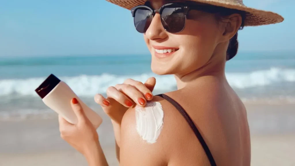 Young woman applying sunscreen, highlighting the importance of sun protection in skincare routine.
